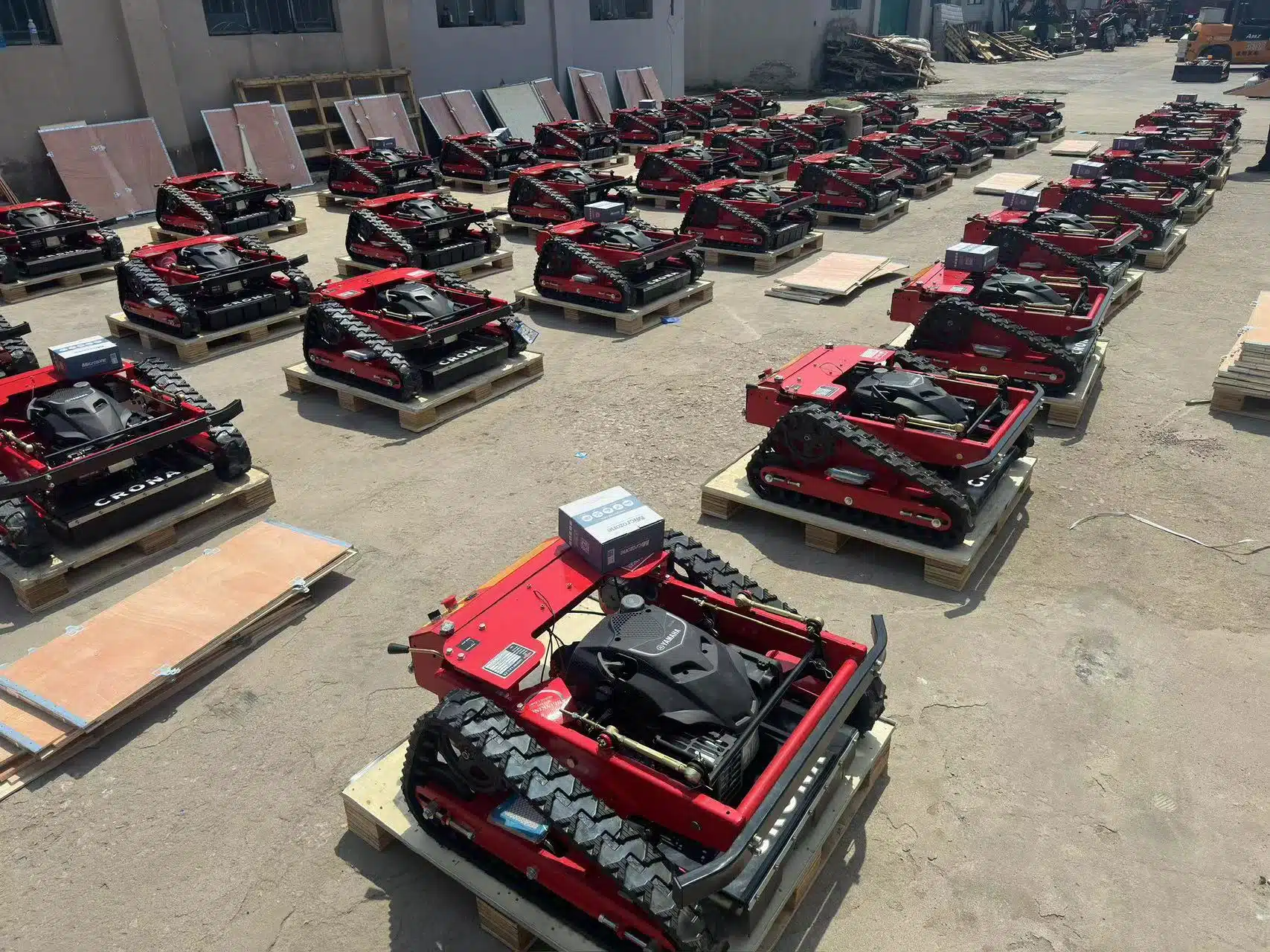 Red tracked robots on pallets in outdoor warehouse