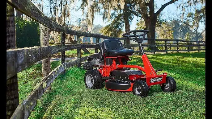 Red riding lawn mower near wooden fence in field