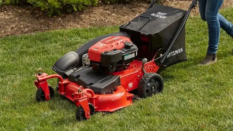 Person using red Craftsman lawnmower on grass
