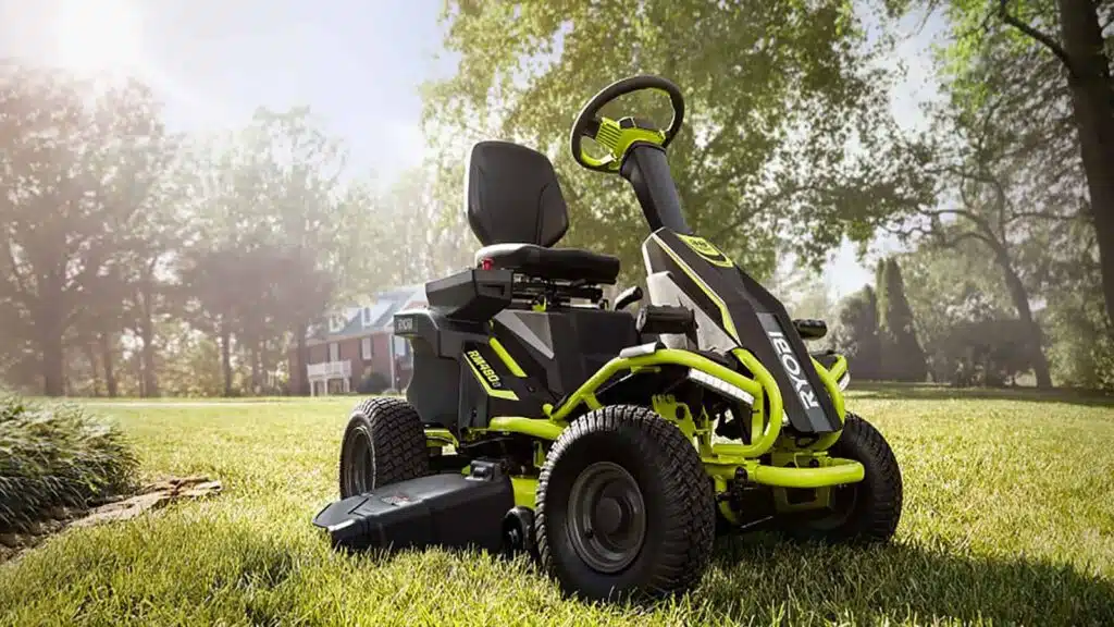 Green battery-powered ride-on lawn mower in sunny yard