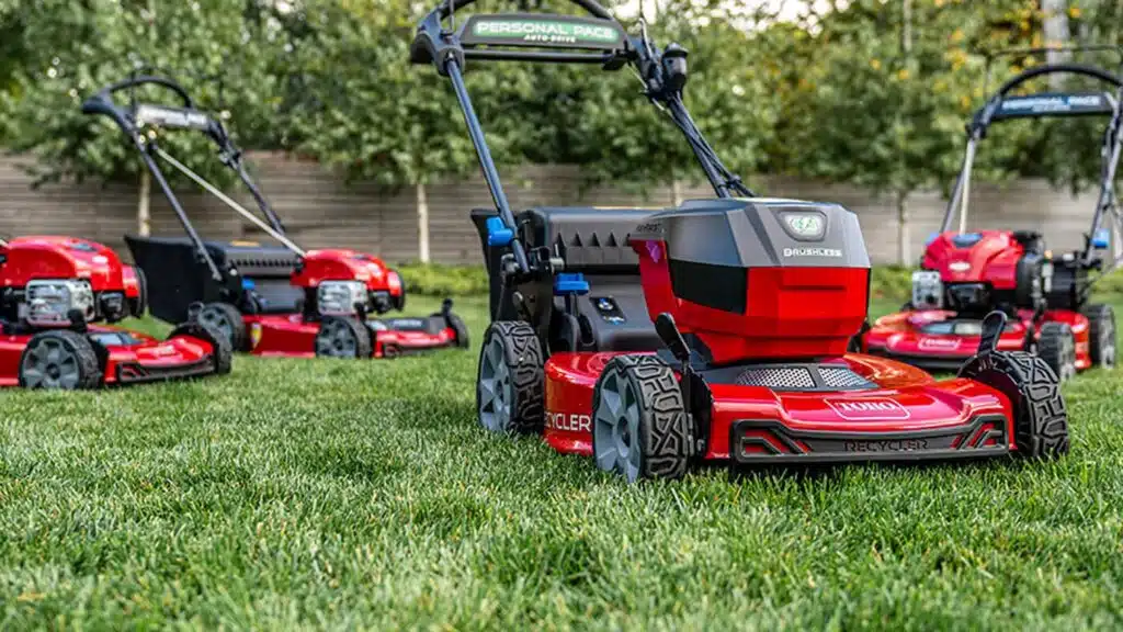 Variety of lawn mowers on green grass in garden