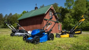 Various lawn mowers in front of red barn